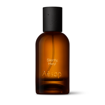 Bernsteinfarbene Flasche des Aesop Silently Hwyl Eau de Parfum aus Glas mit schwarzem Verschluss vor weißem Hintergrund.