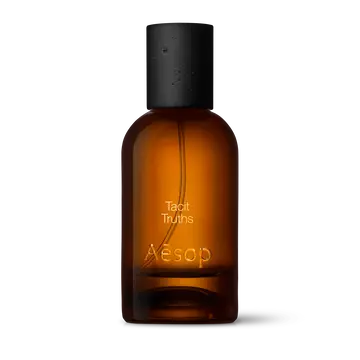 Bernsteinfarbene Flasche des Aesop Tacit Truths Eau de Parfum aus Glas mit schwarzem Verschluss vor weißem Hintergrund.