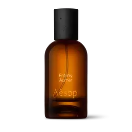 Bernsteinfarbene Flasche des Aesop Entirely Aurner Eau de Parfum aus Glas mit schwarzem Verschluss vor weißem Hintergrund.