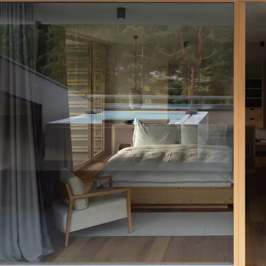 The view from outside a hotel room looking in at a solid timber bed frame and plush white bedding.
