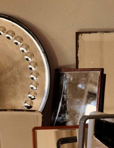 Ubereinandergeschichtete Objekte aus Metall und Stein in Bronze-, Beige- und Dunkelbrauntonen, als sich uberlagernde geometrische Formen vor einer neutralen Wand arrangiert.