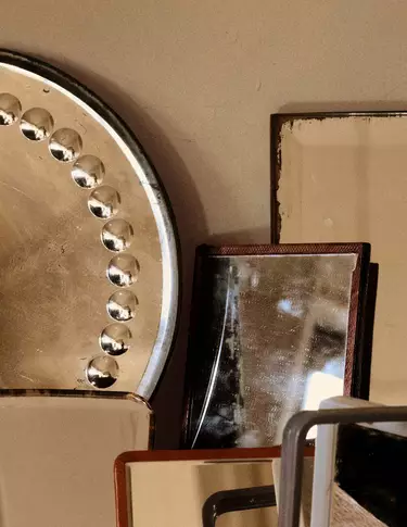 Ubereinandergeschichtete Objekte aus Metall und Stein in Bronze-, Beige- und Dunkelbrauntonen, als sich uberlagernde geometrische Formen vor einer neutralen Wand arrangiert.